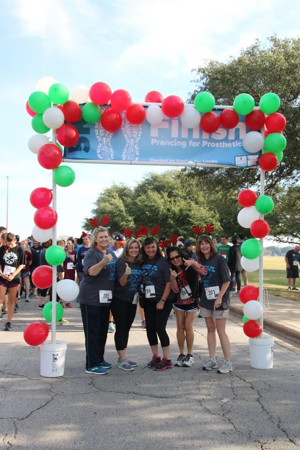 Event Planning Committee in action - Participants posing under a festive balloon arch at the Prancing for Prosthetics finish line