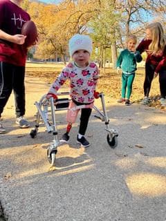 Young child using a walker participating in the event, wearing a floral print top