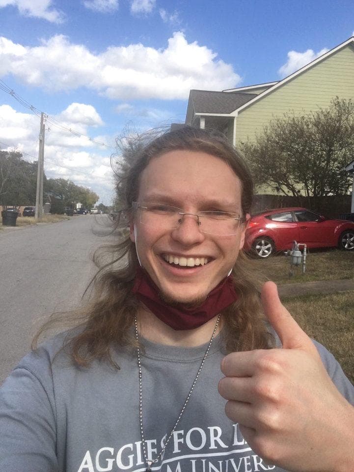 AFL member with maroon neck gaiter giving thumbs up during their walkathon segment on a residential street