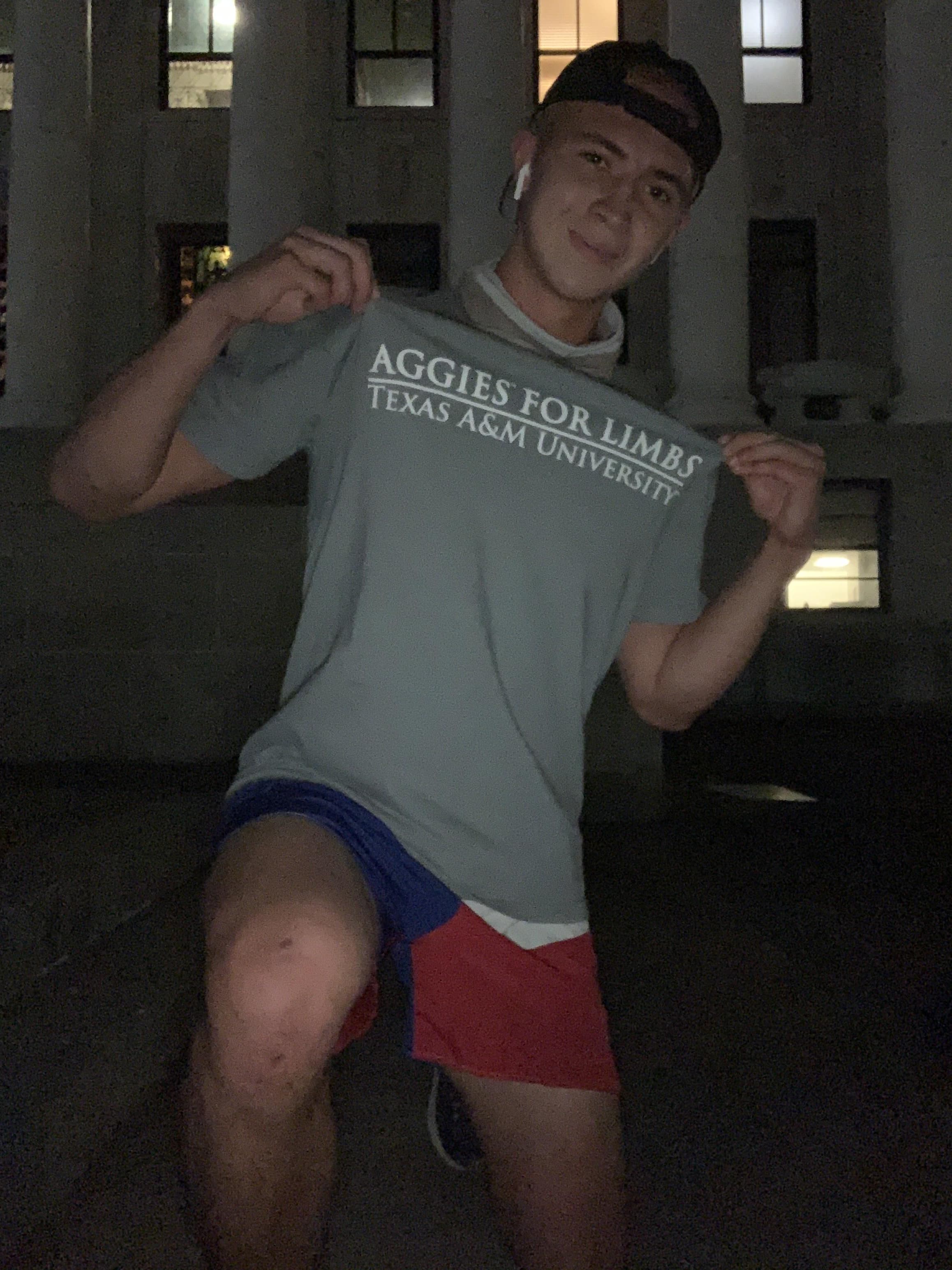 AFL member showing organization t-shirt during nighttime walkathon segment with campus architecture in background